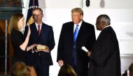 US President Donald Trump watches as Supreme Court Associate Justice Clarence Thomas (R) swears in Judge Amy Coney Barrett as a US Supreme Court Associate Justice, flanked by her husband Jesse M. Barrett, during a ceremony on the South Lawn of the White H