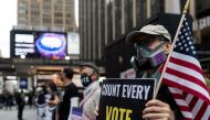 FILE PHOTO: A man wearing a protective mask due to COVID-19 pandemic holds a sign outside Madison Square Garden, which is used as a polling station, on the first day of early voting in Manhattan, New York, U.S. October 24, 2020. REUTERS/Jeenah Moon/File P
