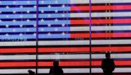 People stand next to a screen displaying a U.S. flag in Times Square during the 2020 U.S. presidential election in New York City, New York, U.S. November 4, 2020. REUTERS/Brendan McDermid