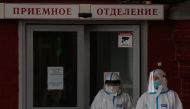 Medical specialists wearing protective gear walk outside a hospital, amid the outbreak of the coronavirus disease (COVID-19) in Saint Petersburg, Russia November 11, 2020. The sign reads: 