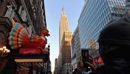 (FILES) In this file photo taken on November 24, 2020, people take photos of Thanksgiving decorations at Macy's Herald Square store in New York City. Thanksgiving is an official American holiday that celebrates one of the country's founding myths. It is f