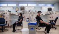 Kassandra Martinez (L), an EVS Attendant and Lead waits for Rachel Marrs (out of frame) to administer the Pfizer-BioNTech Covid-19 Vaccine shot at Rady Children's Hospital in San Diego, California on December 15, 2020. / AFP / ARIANA DREHSLER