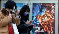 In this picture taken on December 16, 2020, pedestrians walk past a poster promoting the anime movie Demon Slayer -- Kimetsu no Yaiba the Movie: Mugen Train -- at a cinema in Tokyo. An anime epic in which a teenager hunts down and beheads demons has becom
