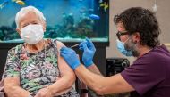 This handout photograph taken and distributed on December 23, 2020 by the Canton of Lucerne shows an unidentified care home resident in her 90s receiving the jab at the start of the Swiss Covid-19 vaccination campaign.  AFP PHOTO / Canton of Lucerne / Key