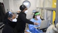 Lab staff wear personal protective equipment (PPE) while collecting tests from travelers in an on-site Covid-19 testing laboratory at Los Angeles International Airport (LAX) on December 31, 2020 in Los Angeles, California. AFP / Patrick T. Fallon
