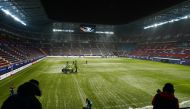 Grounds staff clear snow off the pitch before the match REUTERS/Vincent West
