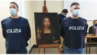 Police officers stand next to a recovered 500-year-old painting titled 'Salvator Mundi' from the school of Leonardo da Vinci, which was stolen from a museum collection in the Basilica di San Domenico Maggiore and was discovered by police in an apartment i