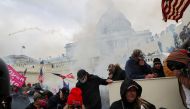 Supporters of US President Donald Trump cover their faces to protect from tear gas during a clash with police officers in front of the US Capitol Building in Washington, US, January 6, 2021. Reuters/Leah Millis/File Photo