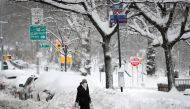 A woman holds shopping bags as she waits at a bus stop near deep snow banks on Manhattan's Upper West Side after a winter storm in New York City, New York, U.S., February 2, 2021. REUTERS/Mike Segar
