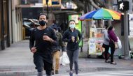 People wearing personal protective face masks jog downtown during the outbreak of the coronavirus disease (COVID-19), in Los Angeles, California, U.S., February 4, 2021. REUTERS/Mario Anzuoni
