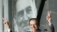 FILE PHOTO: Argentine presidential candidate Carlos Menem stands in front of a giant poster of former President Juan Domingo Peron, as he waves to thousands of followers in River Plate Stadium during the final rally of his campaign, in Buenos Aires, April