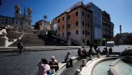 People wearing masks sit near the Spanish steps as COVID-19 restrictions in the Lazio region are slightly relaxed, in Rome, Italy March 30, 2021. REUTERS/Guglielmo Mangiapane
