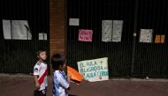 Children walk past placards during a protest outside the Olivos Presidential residence against new restrictions and the closure of schools imposed in the city and Buenos Aires' province amid a rise in coronavirus disease (COVID-19) cases, in Buenos Aires,