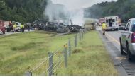 Emergency personnel work at the accident site as smoke rises from the wreckage after about 18 vehicles slammed together on a rain-drenched Alabama highway during Tropical Storm Claudette, in Butler County, Alabama, U.S., June 19, 2021, in this still image