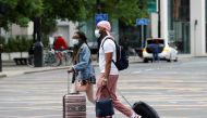 People wear protective masks as they walk with suitcases through the city centre, amid the outbreak of the coronavirus disease (COVID-19) in Manchester, Britain, June 21, 2021. REUTERS/Phil Noble