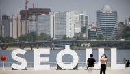 A woman wearing a mask amid the coronavirus disease (COVID-19) pandemic takes photographs of her boyfriend at a Han river park in Seoul, South Korea, May 24, 2021. Reuters/Kim Hong-Ji/File Photo
