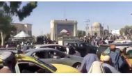 People and cars gather in the Eid Gah Darwaza area as a flag is hoisted on the Kandahar city gate, in Kandahar, Afghanistan in this screen grab taken from a handout video uploaded on social media August 14, 2021. Taliban Handout/via Reuters
