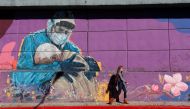 A woman walks past a graffitti depicting a healthcare worker embracing a man, during the coronavirus disease (COVID-19) pandemic, in Cordoba, Argentina, July 10, 2021. REUTERS/Agustin Marcarian/Files

