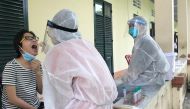 Medical specialists wearing protective hazmat suits take a swab sample to test for the coronavirus disease (COVID-19) from a woman repatriated from Singapore at a military base in southern Mekong delta Dong Thap province, Vietnam August 8, 2020. REUTERS/Mai Nguyen/File Photo