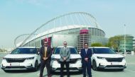 Officials from Kia Qatar and Aayan Leasing pose for a photo with Carnival vehicles at the background, in Doha, recently. 