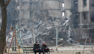 Local residents sit on a bench near an apartment building destroyed in the course of Ukraine-Russia conflict in the besieged southern port city of Mariupol, Ukraine March 25, 2022. REUTERS/Alexander Ermochenko TPX IMAGES OF THE DAY