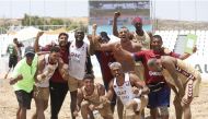 Qatar players and officials celebrate after winning a match during the IHF Beach Handball World Championships in Greece.