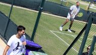 Australia's Nick Kyrgios during training as Serbia's Novak Djokovic walks past after his training. (REUTERS/Toby Melville)