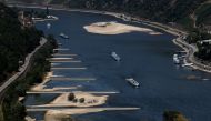 Transport vessels cruise past the partially dried riverbed of the Rhine river in Bingen, Germany, August 9, 2022. REUTERS/Wolfgang Rattay/File Photo