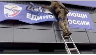 A Ukrainian soldier rips down a banner, amid Russia's invasion of Ukraine, in Vovchansk, Ukraine in this image from a video released September 13, 2022. State Border Service of Ukraine/Handout via REUTERS