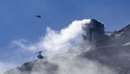An helicopter carries water to stop an ongoing fire at the restaurant Botta at the Glacier 3000 resort in Les Diablerets, Switzerland, September 19, 2022. REUTERS/Denis Balibouse


