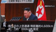 People walk in front of a screen showing North Korea's leader Kim Jong Un in a news report about North Korea firing a ballistic missile over Japan, in Tokyo on October 4, 2022. REUTERS/Issei Kato