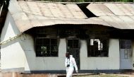 A forensic expert walks past a burnt dormitory building at the Salaama School for the Blind in Luga Village, Ntanzi Parish of Mukono District, near Kampala, Uganda October 25, 2022. REUTERS/Abubaker Lubowa