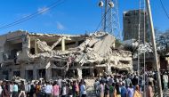 Civilians gather near the ruins of a building at the scene of an explosion along K5 street in Mogadishu, Somalia, October 30, 2022. (REUTERS/Abdirahman Hussein)