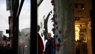 A person walks past the window display of a Guess store which includes the artwork 
