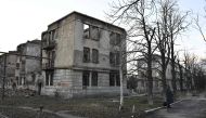 A local resident walks in front of a destroyed residential building in the town of Lyman, Donetsk region, on December 14, 2022, amid the Russian invasion of Ukraine. (Photo by Genya SAVILOV / AFP)