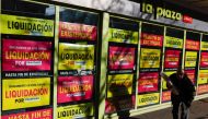 A customer exits a supermarket with posters announcing closing down sales, as the Spanish government announces measures to battle inflation, in Madrid, Spain, December 27, 2022. (REUTERS/Violeta Santos Moura)