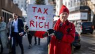 Phil White, a British millionaire poses with a placard reading: 