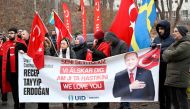 Participants hold Turkish flags and a banner reading 'Recep Tayyip Erdogan - We love you' during a demonstration of the pro-Turkish organization Union of European Turkish Democrats in support of Turkey and President Recep Tayyip Erdogan outside the Turkish Embassy in Stockholm, Sweden, on January 21, 2023.(Photo by Fredrik Sandberg / TT News Agency / AFP)