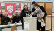 A Cypriot man carries his daughter as he votes in presidential elections with his daughter at a Limassol polling centre on February 5, 2023.  (Photo by Iakovos Hatzistavrou / AFP)