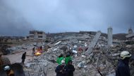Syrian rescue workers gather amidst collapsed buildings on February 6, 2022 in the town of Sarmada, in Syria's rebel-held northwestern Idlib province, as a search operation continues following a deadly earthquake. - At least 1,400 people were killed and 3,411 injured across Syria today in an earthquake that had its epicentre in southwestern Turkey, the government and rescuers said. (Photo by AAREF WATAD / AFP)
