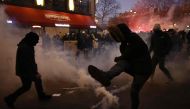 A protester kicks back a tear gas canister as clashes erupt during a demonstration on the third day of nationwide rallies and strikes against a pensions reform plan at Republique square in Paris on February 7, 2023. (Photo by Sameer Al-Doumy / AFP)