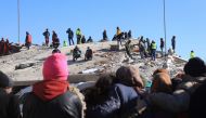 People watch as rescuers and civilians look for survivors under the rubble of collapsed buildings in Nurdagi, in the countryside of Gaziantep, on February 9, 2023, three days after a deadly earthquake that hit Turkey and Syria. Photo by Zein Al RIFAI / AFP