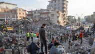 People stand on top of rubble of collapsed buildings during rescue operations in Hatay on February 12, 2023, after a 7,8 magnitude earthquake struck the border region of Turkey and Syria earlier in the week. (Photo by BULENT KILIC / AFP)