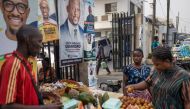 A woman buys fruits from a street vendor nexy to a campaign poster of presidential candidate of the ruling Action Progressives Congress (APC) Bola Ahmed Tinubu and running mate Kashim Shettima in a market in Lagos on February 16, 2023. (Photo by Michele Spatari / AFP)