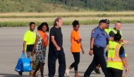 Bryce Barker (C), who was held for a week in the Papua New Guinea highlands by an armed group, is escorted from a plane following his release in Port Moresby on February 26, 2023. (Photo by AFP)