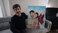 Turkish father Mesut Hancer, poses and holds a painting representing him and his daughter Irmak in his appartment in Ankara on February 25, 2023, as his family tries to rebuild, after losing their daughter Irmak, 15 years old, in the earthquake that devastated the southeastern region of Turkey. Photo by Adem ALTAN / AFP