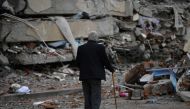 A man walks among debris of collapsed buildings in Kahramanmaras, on March 4, 2023, one month after a massive earthquake struck south-east Turkey. Photo by Eylul YASAR / AFP