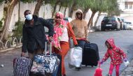 Sub-Saharan migrants head with their belongings to a bus taking them to a repatriation flight, leaving Tunis for their countries of origin. (Photo by FETHI BELAID / AFP)