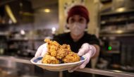 This picture taken on March 1, 2023 shows Hiromi Matsumoto serving a plate of karaage, a Japanese style fried chicken at an izakaya food store in Tokyo. Photos by Philip FONG / AFP