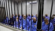 Jihadists accused of being members of the Islamic State (IS) group sit in the defendant booth during their trial, in the northwestern Libyan city of Misrata on May 29, 2023. (Photo by Mahmud Turkia / AFP)